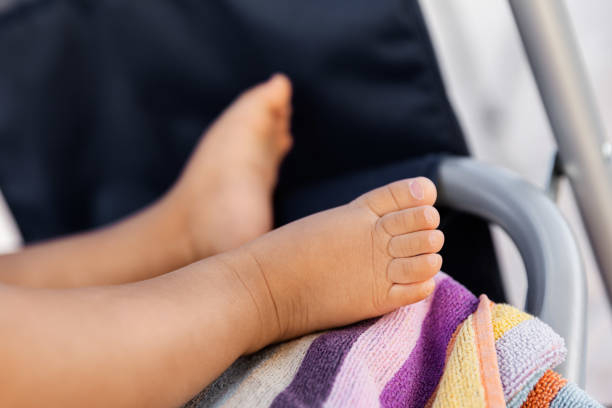 Infant baby legs resting on the beach towel in the summer, tiny feet at natural light stock photo