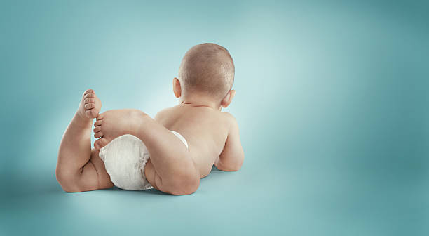 Infant child baby toddler laying in diapers. Back view stock photo