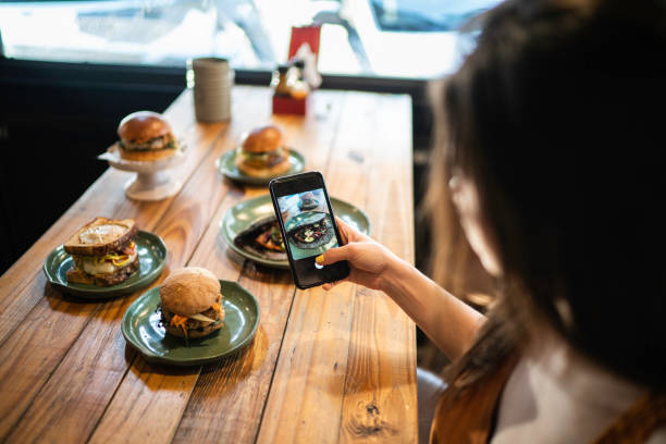 Influencer woman filming the hamburger table Influencer woman filming the hamburger table unhealthy eating photos stock pictures, royalty-free photos & images