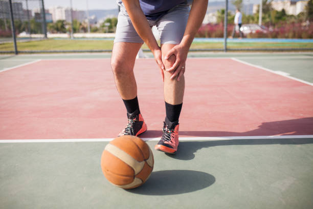 Injured basketball player holding his leg in pain  stock photo Injured basketball player holding his leg in pain  stock photo human joint stock pictures, royalty-free photos & images