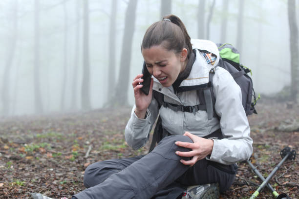 Injured hiker suffering knee fracture asking for help on phone stock photo