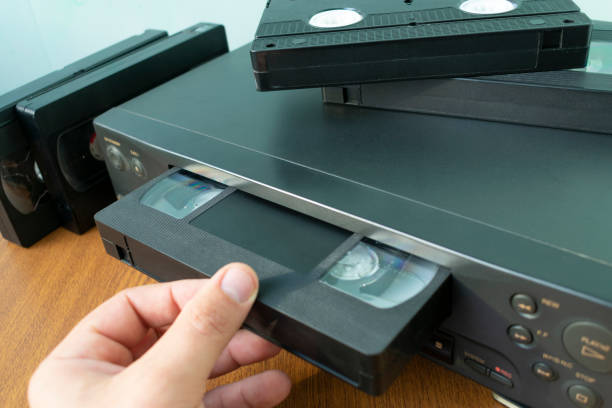 insert a videotape into a tape recorder VHS videocassette is put into the video recorder to watch the video, another video cassette is on the video-tape recorder dvd stock pictures, royalty-free photos & images