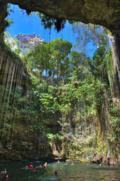 Inside of Ik Kil Cenote, near Chichen Itza, Mexico. Lovely cenote with transparent waters and hanging roots. Natural swimming pool, people swimming, adventure place. in Yucatan, Mexico - Mar 2, 2018 stock photo