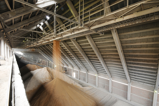 Huge pile of sand under conveyer belt in a cement factory. Cement factory machinery. industrial plant with silos and infrastructure.
