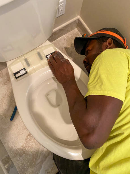 Installing a bidet toilet seat Electrician is installing a new bidet toilet seat in a home bathroom. african american plumber stock pictures, royalty-free photos & images