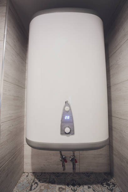 Instant tankless electric water heater installed on white tile wall with input and output pipe outlet and elcb safety breaker system. stock photo