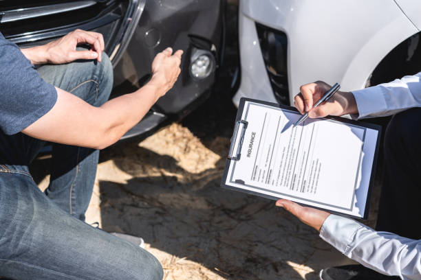 Insurance Agent examining car crash and customer assessed negotiation, checking and signing on report claim form process after accident collision, Accident and insurance concept stock photo