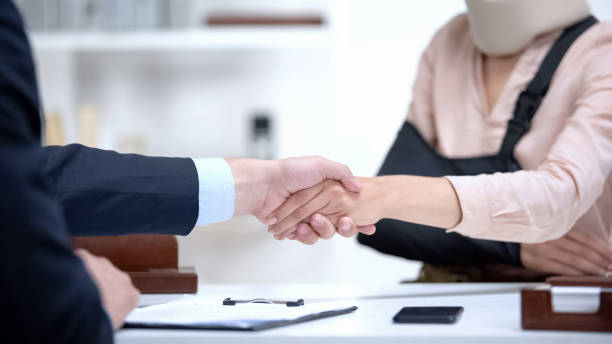 Insurance agent shaking hand with woman in arm sling, psychological support stock photo