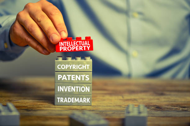 Intellectual property Businessman staking plastic block blocks. He is adding a red block showing the words ’Intellectual property’ on top of grey blocks with related words intellectual property stock pictures, royalty-free photos & images