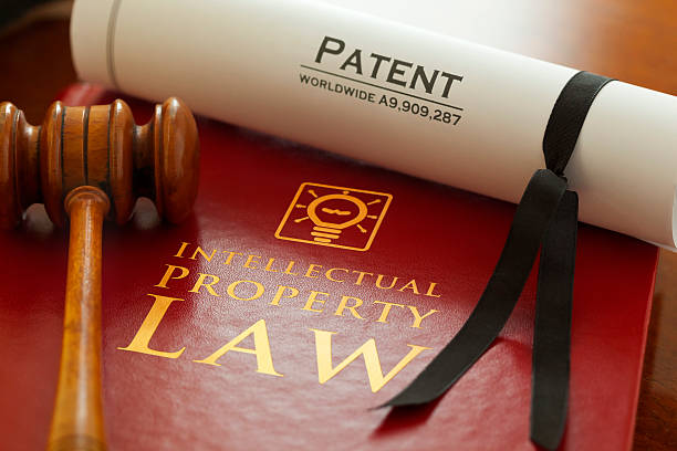 Intellectual Property Inspector. Graphic logo is my artwork. Patent Number is fictitious. Thanks.     Red leather Intellectual Property Law book with with gold embossed type and iconic light bulb, ideas icon logo, with a judges gavel and a generic A4 Patent document. intellectual property stock pictures, royalty-free photos & images