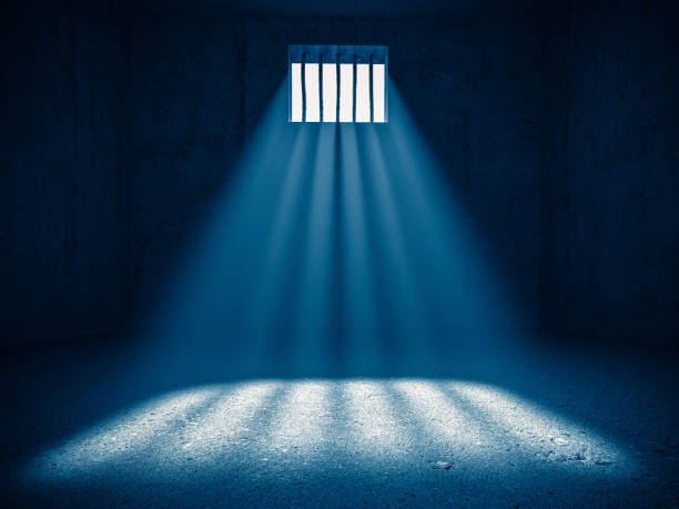 interior of a prison, light from a barred window. stock photo