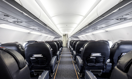 Empty commercial airplane cabin interior with leather seats.