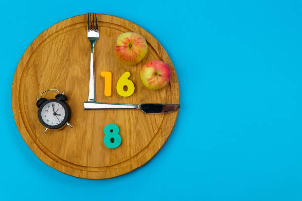 Intermittent fasting concept 16:8. Intermittent Fasting often use for losing weight or to control diabetes. Blue background stock photo