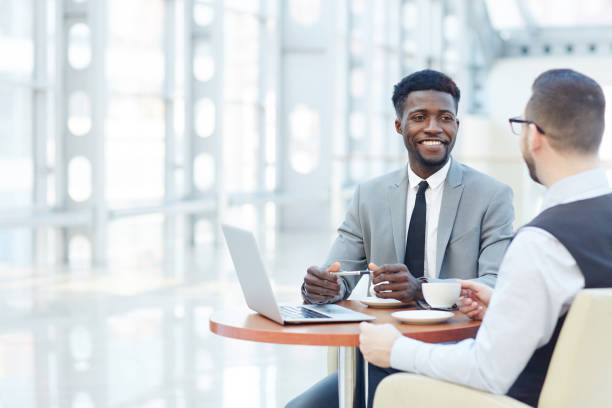 International Business Meeting Portrait of successful African-American businessman smiling during meeting with colleague at coffee break advice stock pictures, royalty-free photos & images