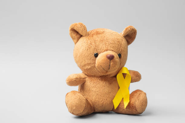 International Childhood Cancer Awareness month, Children toy with golden color Ribbon for supporting kids living. Healthcare and World cancer day concept stock photo