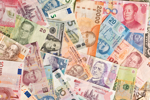 A colorful variation and collection of international currency, a global business money exchange and finance. Photographed in studio, at high angle in horizontal format.
