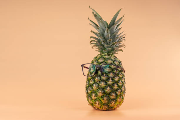 Interpretation of pineapple fruit in a human image as in ophthalmic medicine with glasses on a yellow background. Copy space stock photo
