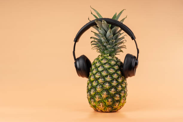 Interpretation of pineapple fruit in a human image with headphones for listening to music concept of relaxation and relaxation on vacation. stock photo