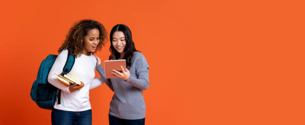 interracial college students friends looking at tablet computer - friends color background imagens e fotografias de stock