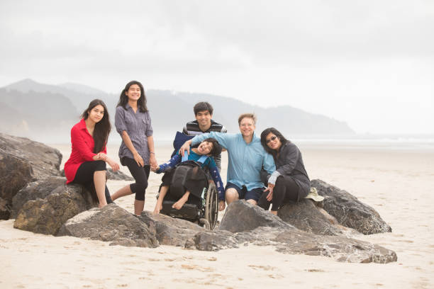 Interracial family of six on beach with special needs child stock photo