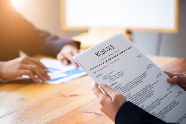 Interviewer reading a resume, Person submits job application, Person describe yourself to interviewer, Close up view of job interview in office, focus on resume, recruiter considering application, hr manager making hiring decision  resume stock pictures, royalty-free photos & images