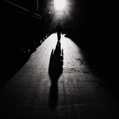 man walking against the sun on the street.