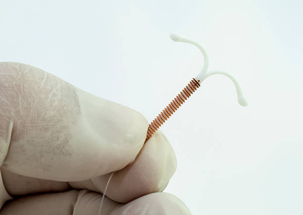 Intrauterine device Latex gloved hand holding an intrauterine device (IUD or coil). iud stock pictures, royalty-free photos & images