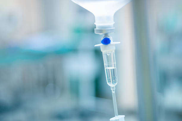 Intravenous therapy iv infusion set and bottle on a pole. Liquid saline is slowly dripping drops of drugs, medicine or antibiotic therapy and surgery recovery in a hospital or clinic stock photo