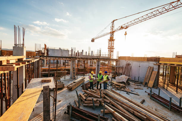 Investors and contractors on construction site Construction industry concept - architects and engineers discussing work progress between concrete walls, scaffolds and cranes. construction stock pictures, royalty-free photos & images
