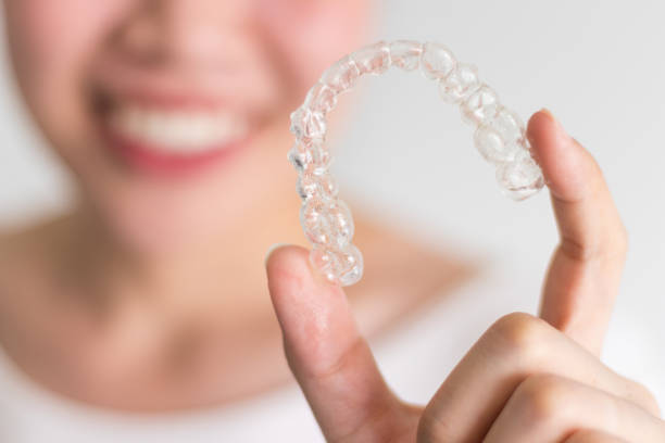 Invisalign braces A smiling woman holding invisalign or invisible braces, orthodontic equipment dental braces stock pictures, royalty-free photos & images