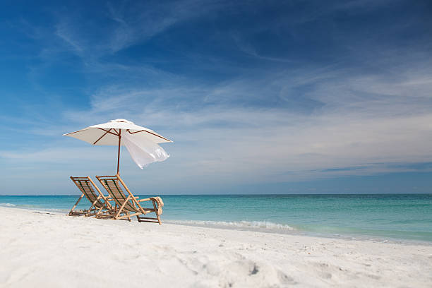 einladende stühle und sonnenschirm am strand in florida, usa - liegestuhl stock-fotos und bilder
