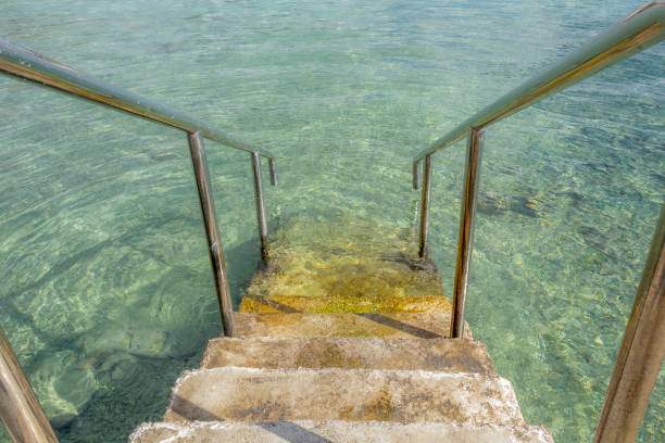 Inviting stairs leading into clear blue ocean water stock photo