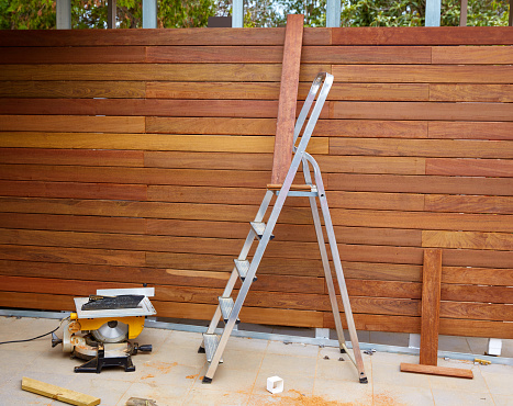 Ipe wood fence installation with carpenter table circular saw and sawdust