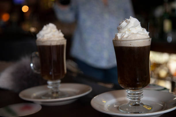 Irish Coffee - Pouring an Irish Cream Liqueur on Top of the Whipped Cream stock photo