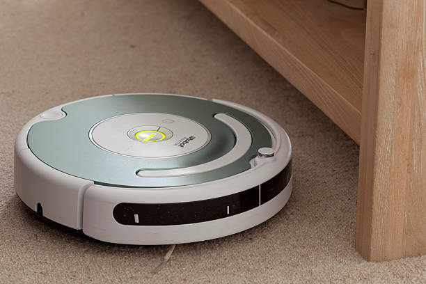 iRobot Roomba Robot Vacuum Cleaner Brisbane, Australia - October 17, 2011: iRobot Roomba Robot Vacuum Cleaner cleaning carpet around a wooden coffee table. roomba stock pictures, royalty-free photos & images