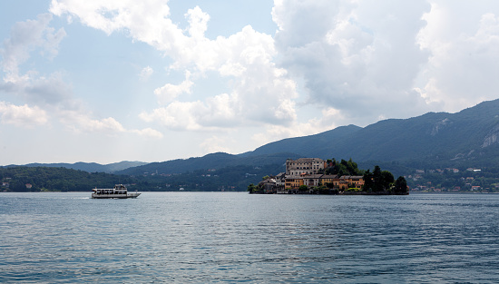 A tour boat approaching the monastery island Isola San Giulio in the small lake Lago d'Orta located in the Piedmont region of Italy