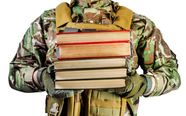 Isolated photo of a soldier in uniform holding stack of books. Isolated photo of a soldier in uniform holding stack of books on white background, front view. military schools stock pictures, royalty-free photos & images