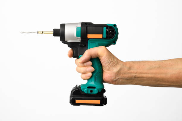 Isolated shot of hand holding a cordless drill and twist bit with screw on white background stock photo