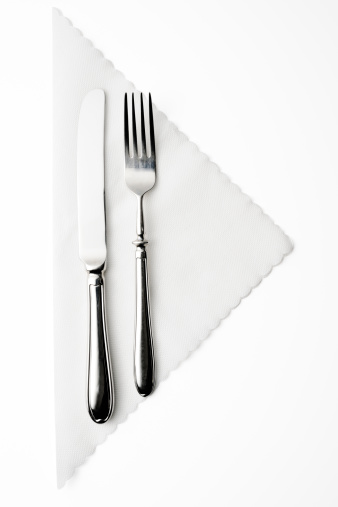 Silver knife and fork on white paper napkin isolated on white background with clipping path.