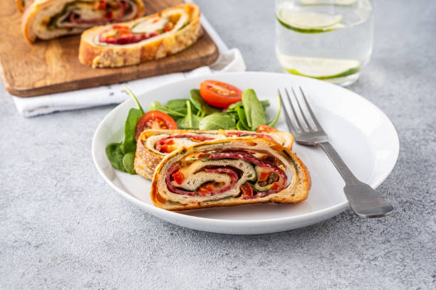 Italian food Pizza roll stromboli with cheese, salami, spinach and red pepper a light background. stock photo