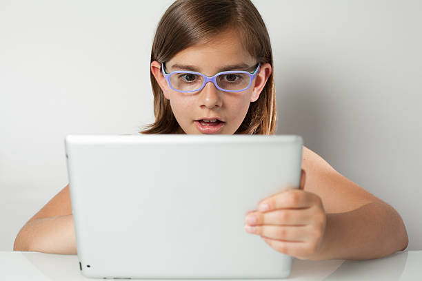 Italian Little Girl Surprised in front of a Tablet PC stock photo