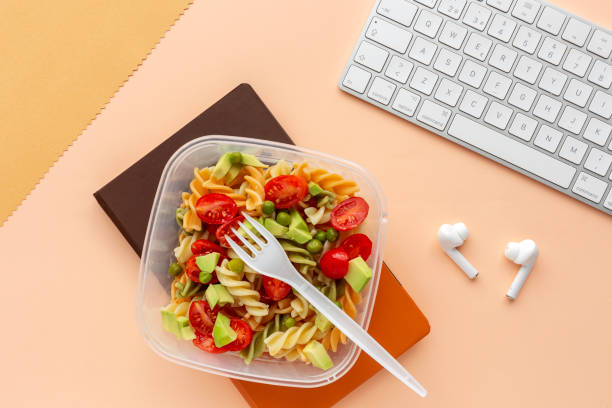 Italian pasta with vegetables on office desk with keyboard stock photo