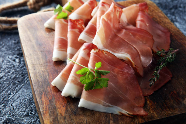 Italian prosciutto crudo or jamon with parsley. Raw ham stock photo