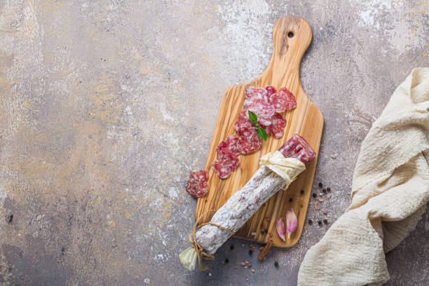 Italian salami on wooden board with cheese and olives stock photo