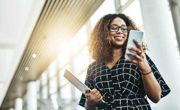 It's all easier when done digitally Low angle shot of an attractive young businesswoman using a smartphone in a modern office businesswoman stock pictures, royalty-free photos & images