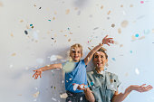 Photo of smiling mother and daughter throwing colorful confetti