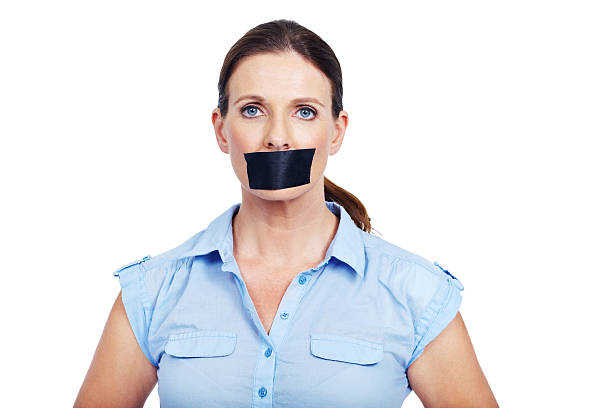 It's confidential Portrait of serious woman with tape on her mouth - conceptual human mouth gag adhesive tape women stock pictures, royalty-free photos & images