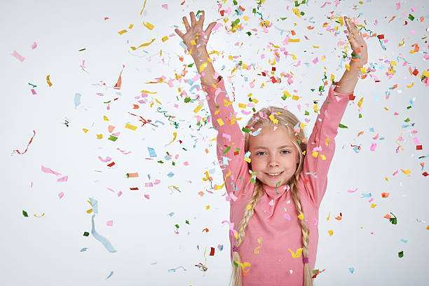 Studio shot of a happy little girl with confetti falling all around...