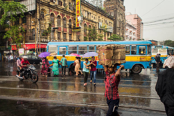 It's raining in Kolkata! Kolkata,India- June 1, 2014: This is a typical monsoon afternoon in Kolkata.It's still raining in so in the picture people are crossing the streets with umbrelas.  Shot near Esplande street in Kolkata.  kolkata stock pictures, royalty-free photos & images
