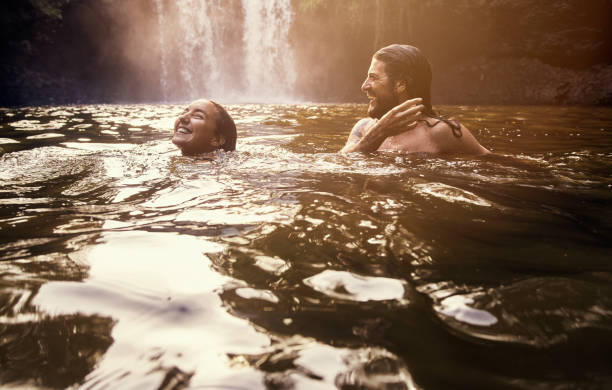 It's so blissful out here Shot of a young couple swimming together in a lake waterfalls stock pictures, royalty-free photos & images